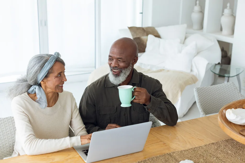 Couple having coffee and scheduling hearing text appointment on laptop